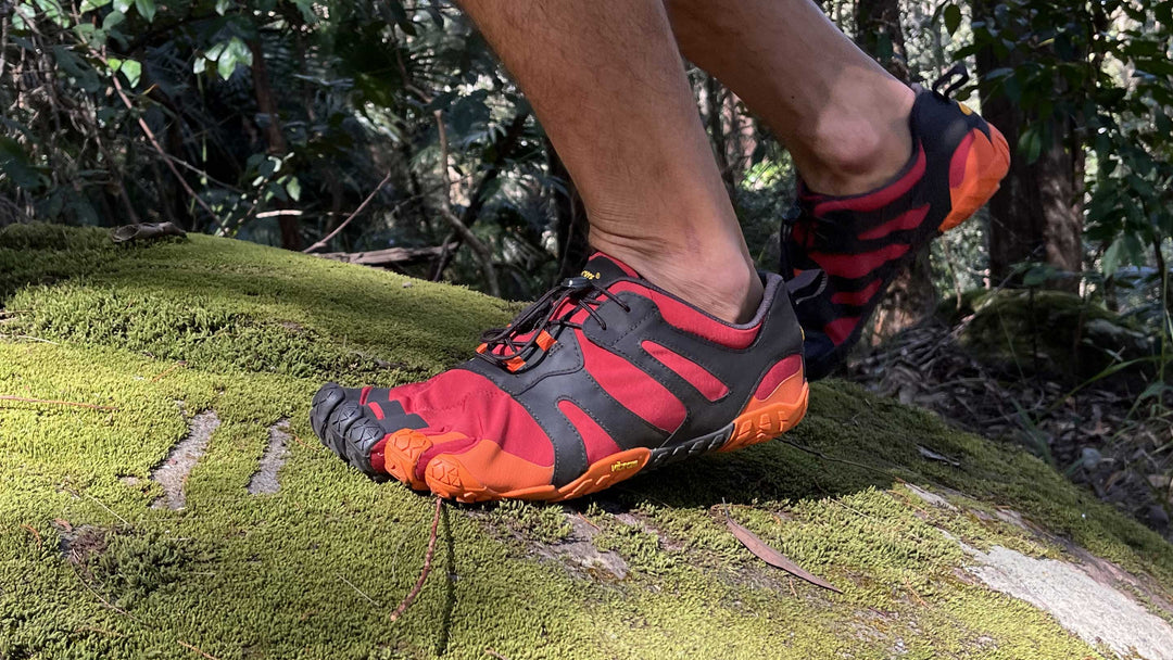 Vibram V-Trail V2 in Red walking over a rock